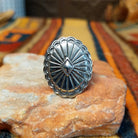 Silver Concho Ring by Elgin Tom featuring an oval silver concho with radiating stamped patterns, a raised diamond-shaped center, scalloped edges, and contrasting oxidized detailing.