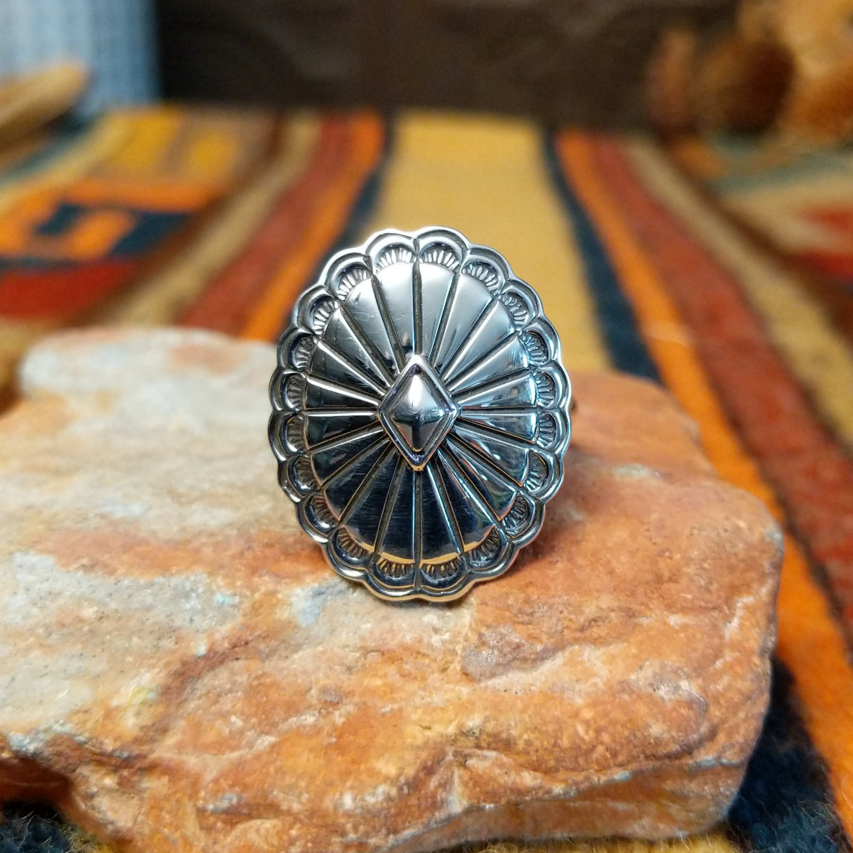 Silver Concho Ring by Elgin Tom featuring an oval silver concho with radiating stamped patterns, a raised diamond-shaped center, scalloped edges, and contrasting oxidized detailing.