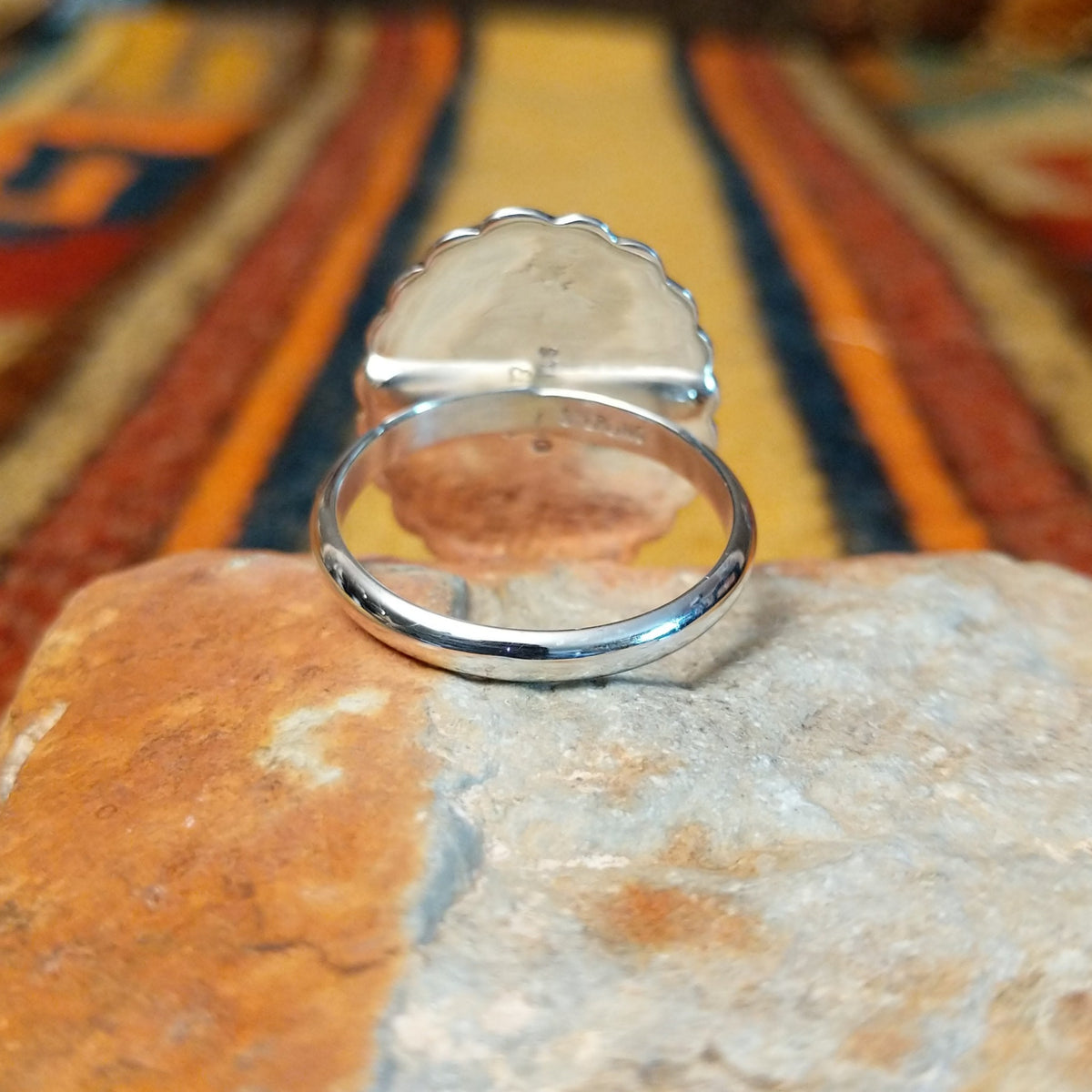 Silver Concho Ring by Elgin Tom featuring an oval silver concho with radiating stamped patterns, a raised diamond-shaped center, scalloped edges, and contrasting oxidized detailing; underside view.