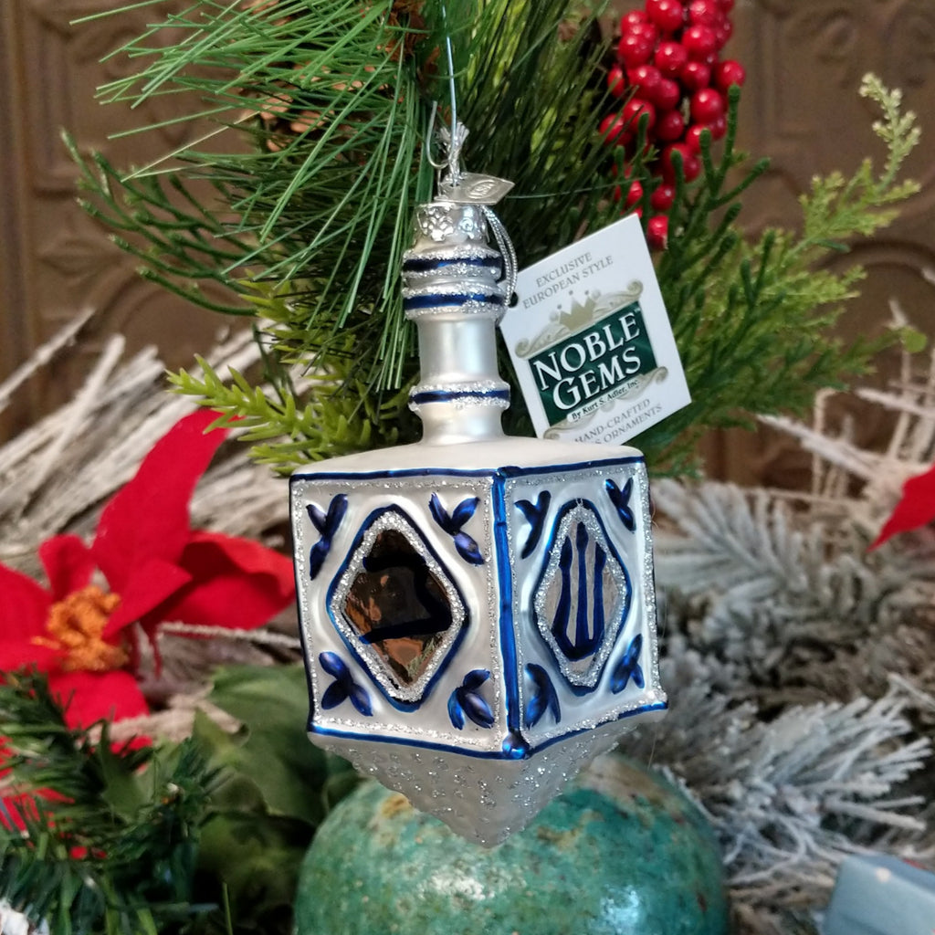 Glass crafted into a European style dreidel in the colors silver and blue with traditional symbols.