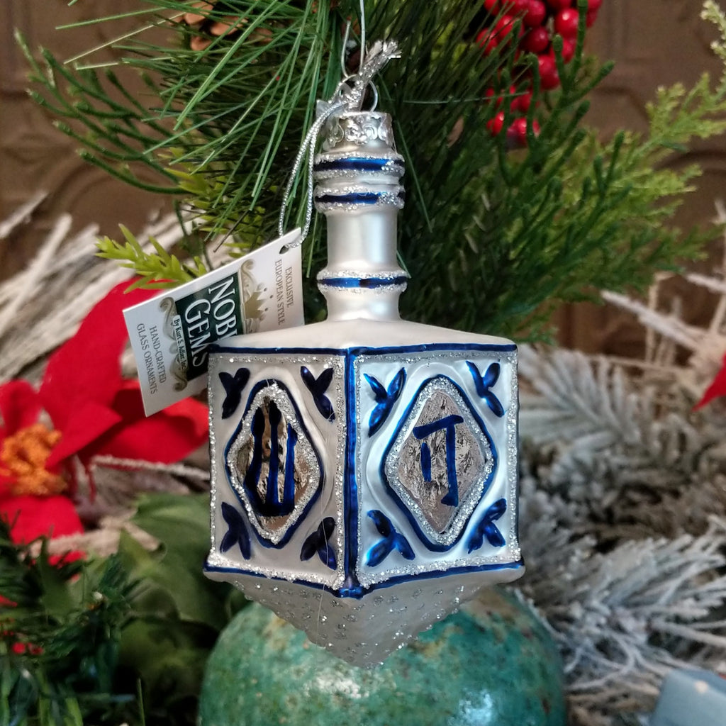Glass crafted into a European style dreidel in the colors silver and blue with traditional symbols.