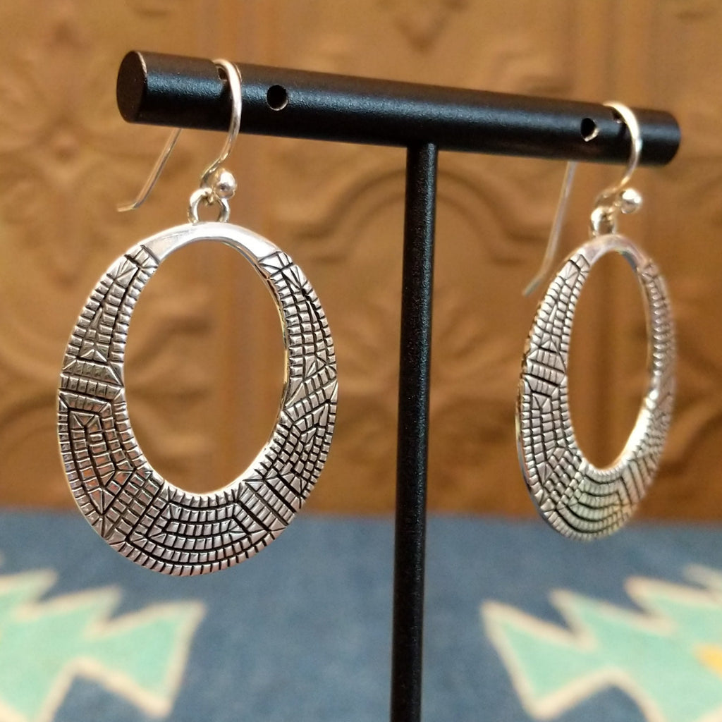 Sterling silver earrings crafted into eclipse silhouettes with geometric stamping.