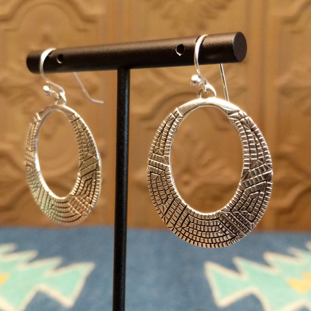Sterling silver earrings crafted into eclipse silhouettes with geometric stamping.