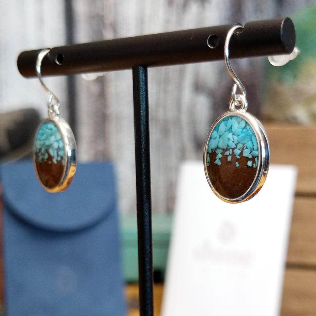 Oval earrings with a silver-plated brass frame, featuring turquoise and sand.