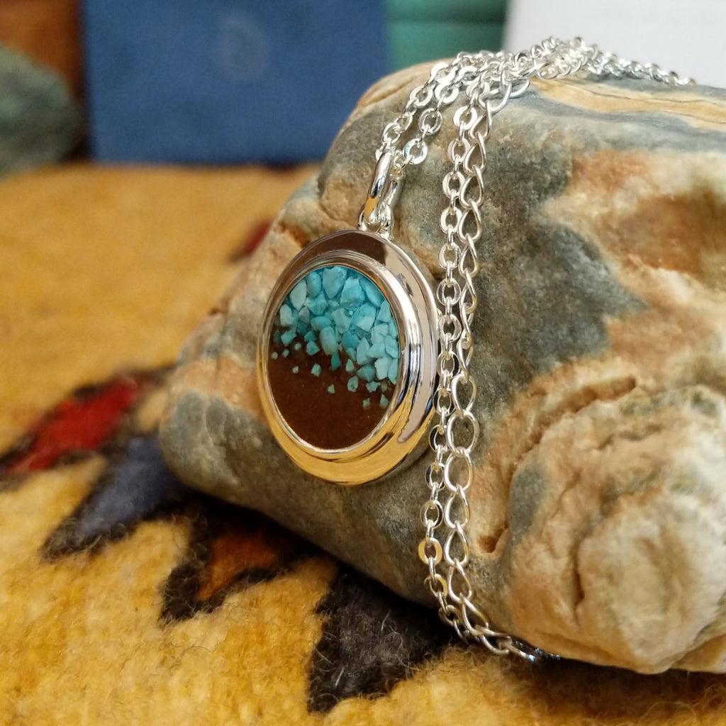 Round necklace pendant with a silver-plated brass frame with turquoise and sand.