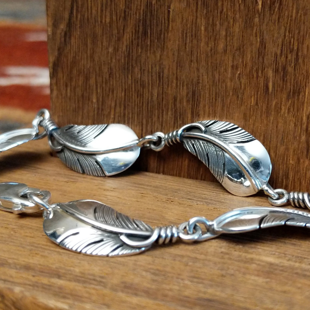 Sterling silver feather link bracelet with polished finish.