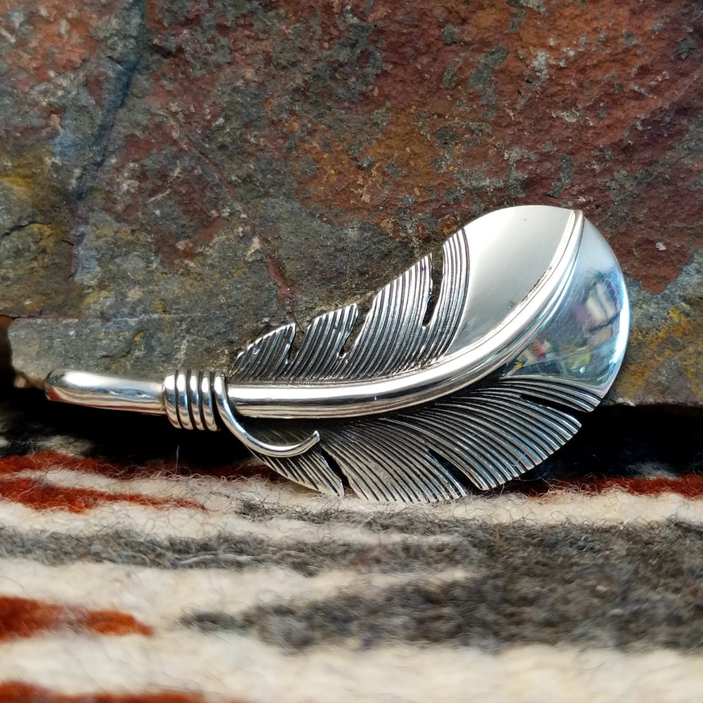 Sterling silver feather pendant with a polished finish.