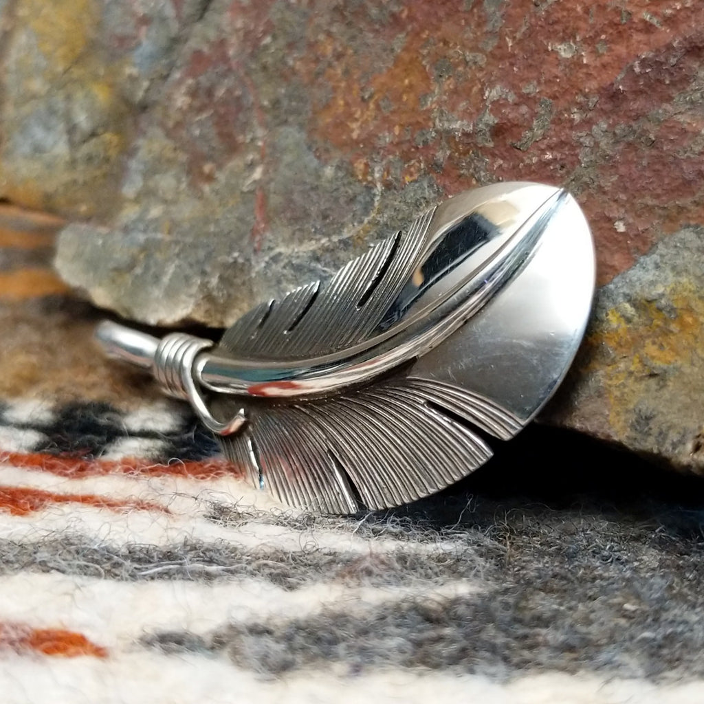 Sterling silver feather pendant with a polished finish.