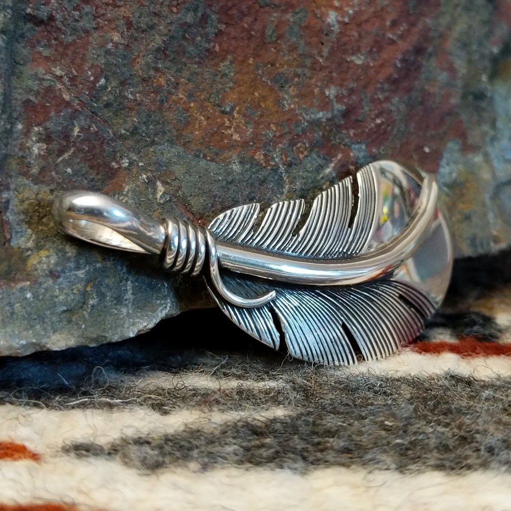 Sterling silver feather pendant with a polished finish.