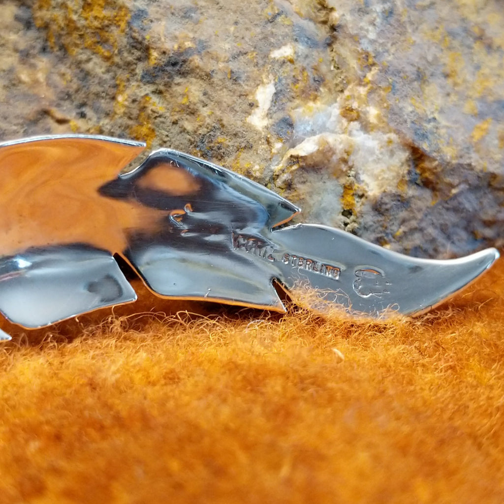 The authentication stamp is found on the back of the feather pendant.