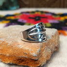 Wide silver feather ring by L.P. with detailed stamped lines and a raised center spine.