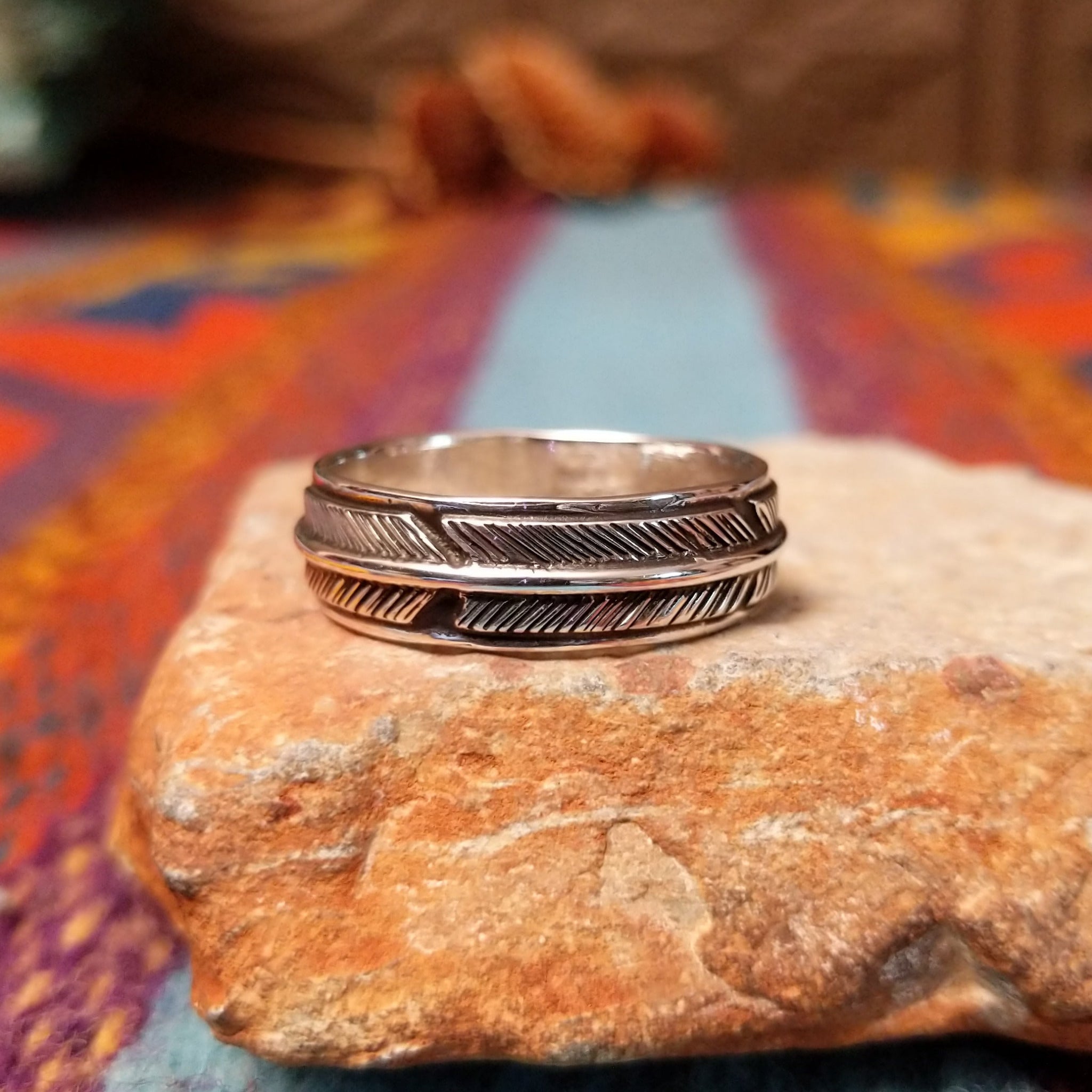 Silver Feather Ring by Raymond Coriz featuring a continuous detailed feather pattern with textured lines, darkened accents, and polished Sterling Silver borders.