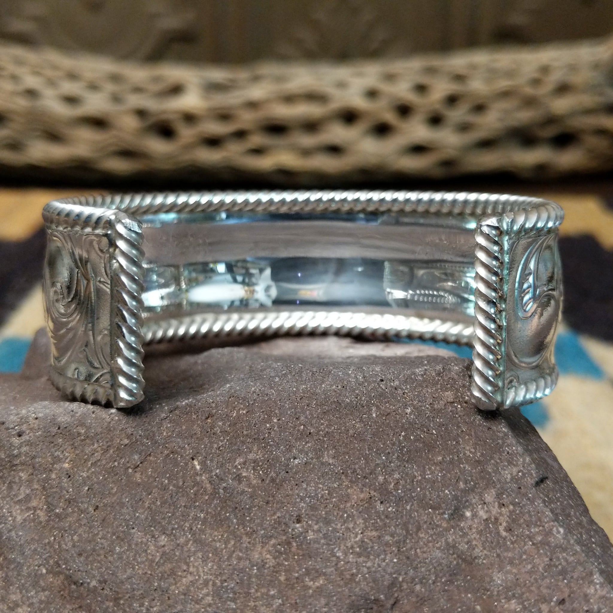 Silver filigree cuff by Larry Joe, featuring hand-engraved scrollwork framed by twisted rope borders on a handcrafted wide sterling silver open cuff.  Underside view.
