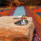Polished silver saddle ring by Raymond Coriz with broad curved face.