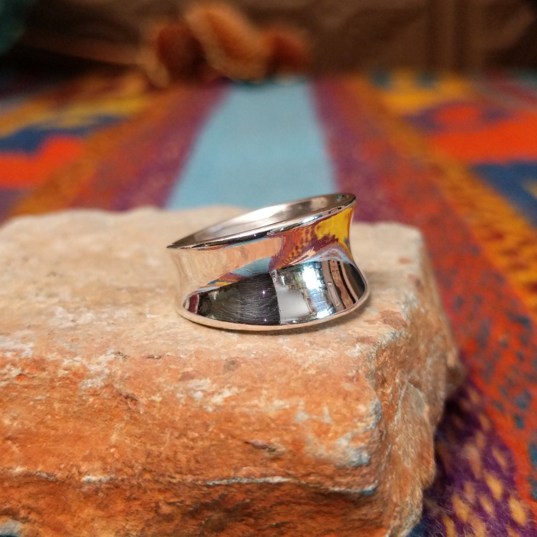 Polished silver saddle ring by Raymond Coriz with broad curved face.