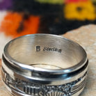 Silver spinner ring by Elaine Becenti with stamped geometric designs and layered movable bands. Close up of the artist's stamped signature.