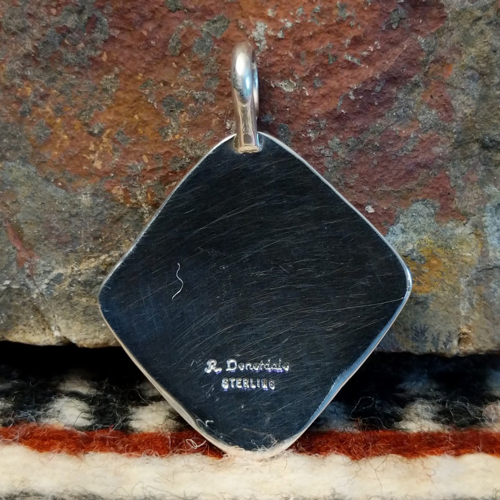 The back features the artisan's signature.