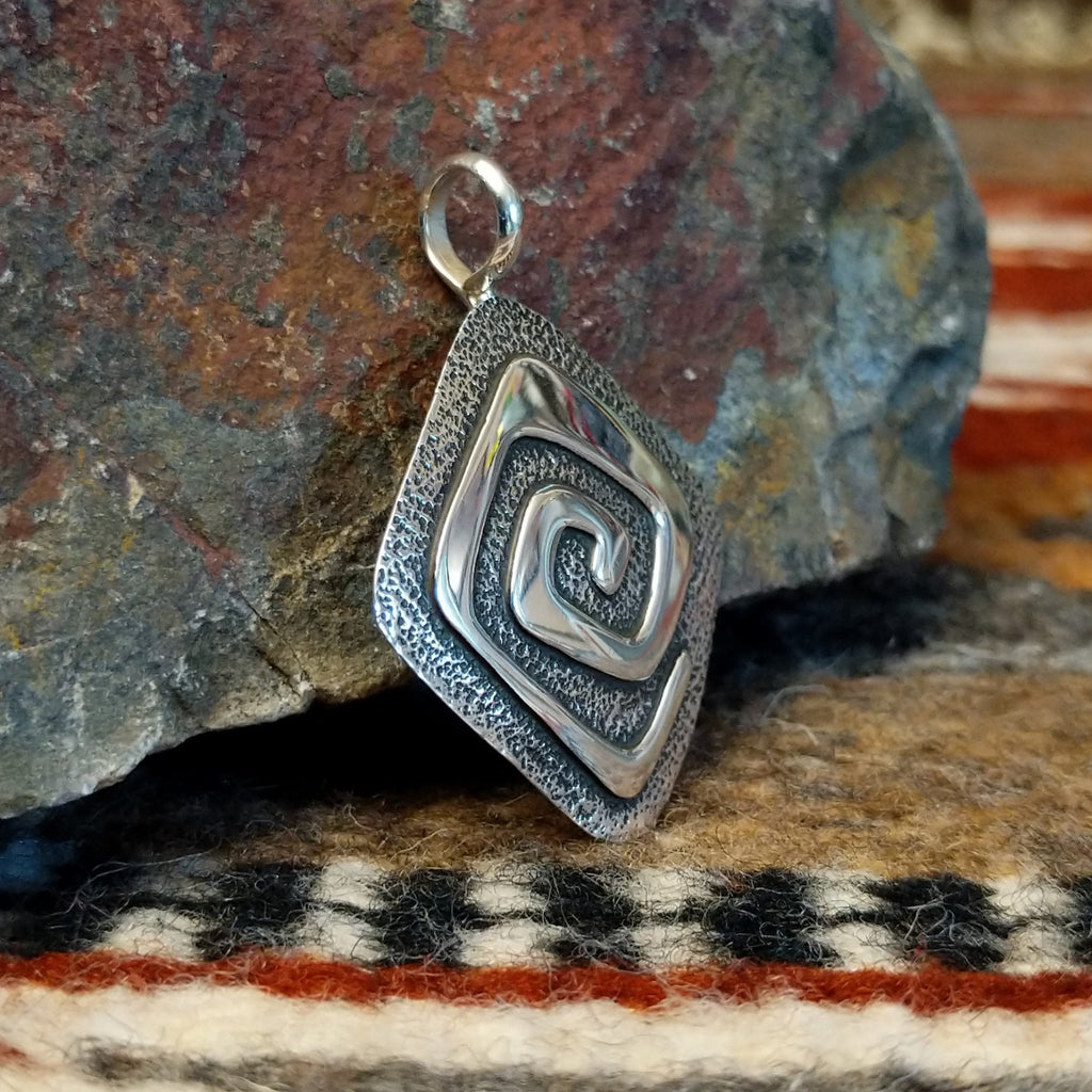 Diamond shaped sterling silver pendant with hammered finish and polished spiral design.