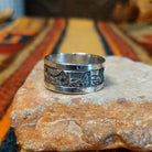 Silver Storyteller Ring by Elaine Becenti featuring a wide silver band with detailed landscape motifs, textured mountain designs, oxidized accents, and polished edges.