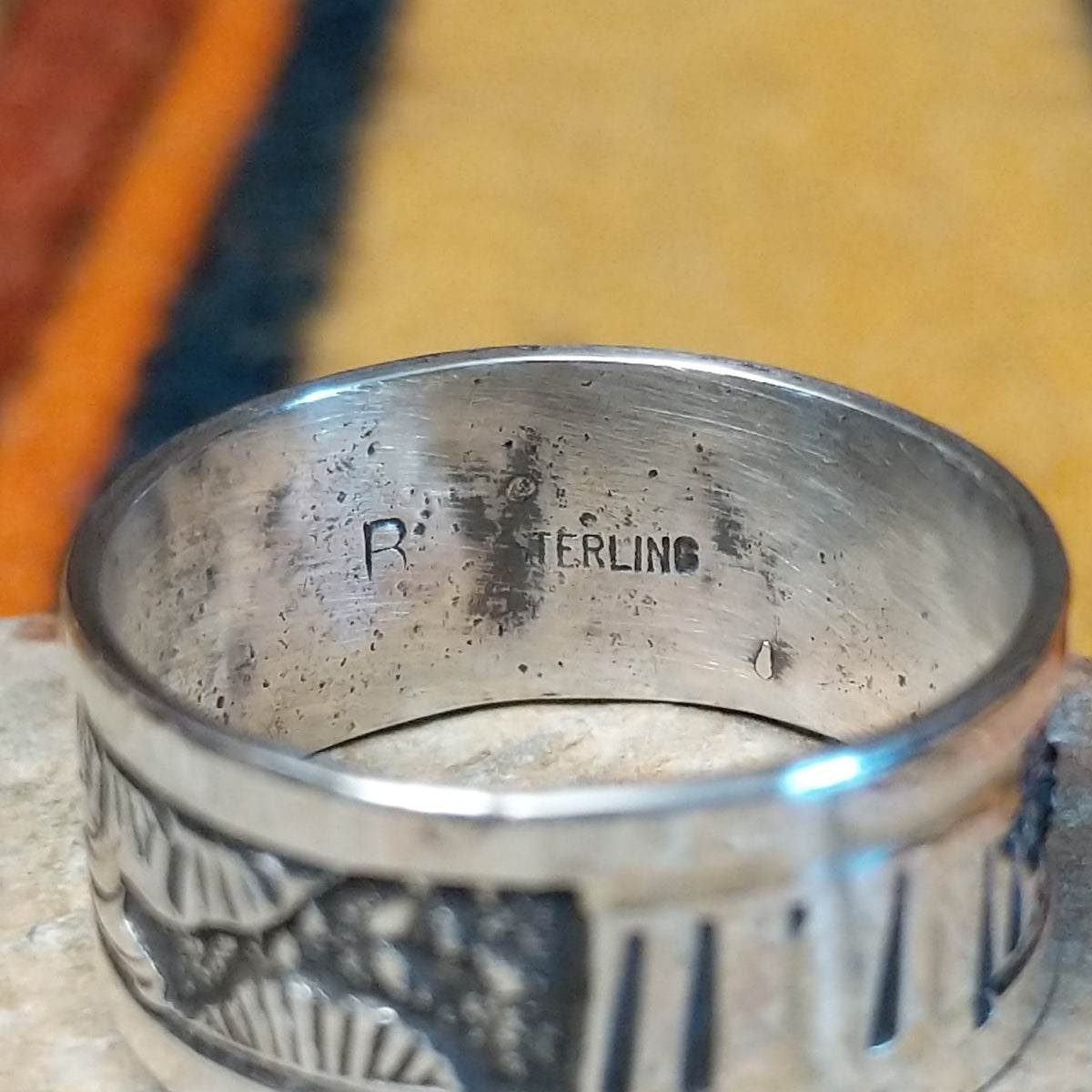 Silver Storyteller Ring by Elaine Becenti featuring a wide silver band with detailed landscape motifs, textured mountain designs, oxidized accents, and polished edges; artisan and Sterling Silver stamp.