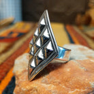 Silver ring by Dakota T. Willie featuring an elongated diamond-shaped face with nine raised, polished studs arranged within textured geometric borders. Ring shown from the side to show the band.