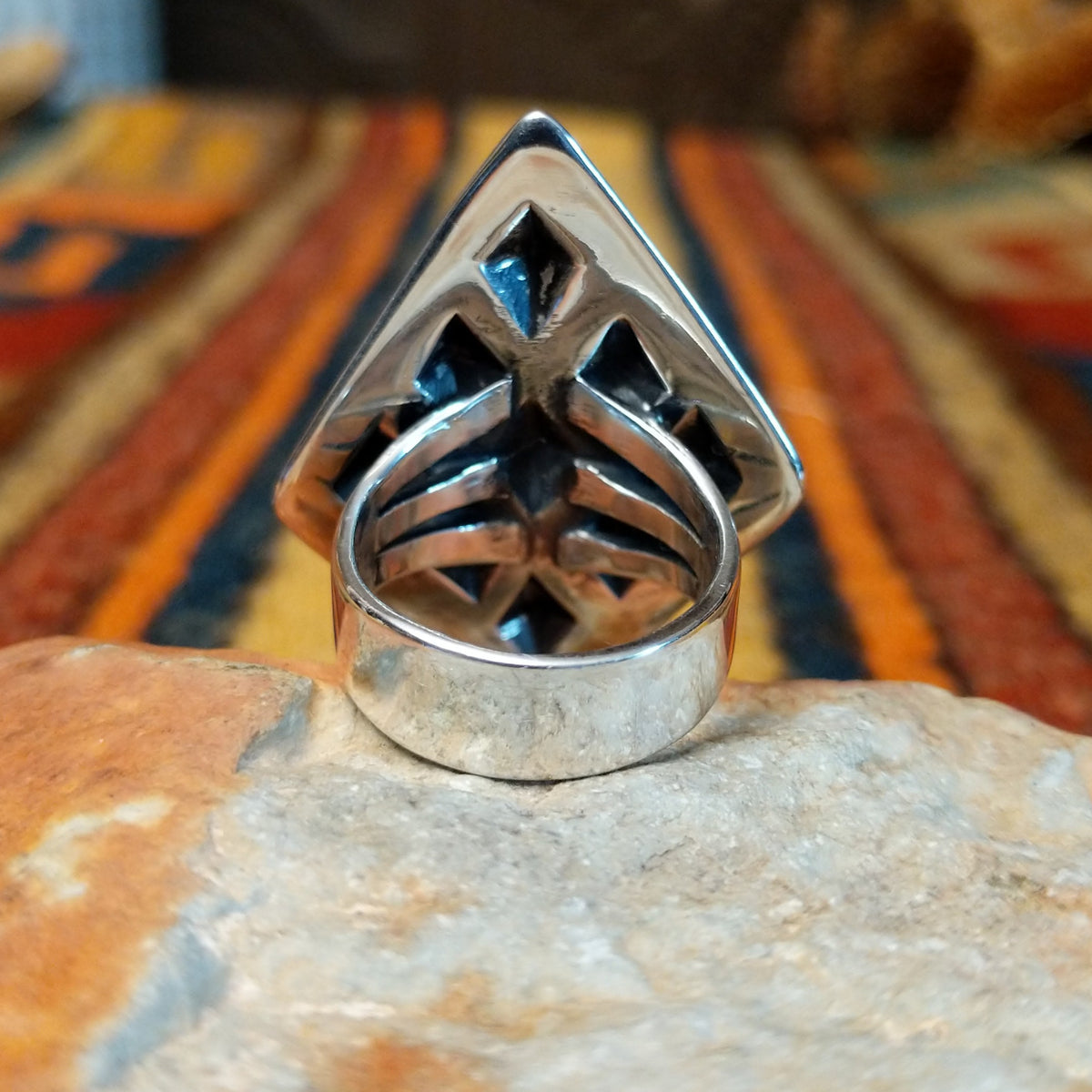 Silver ring by Dakota T. Willie featuring an elongated diamond-shaped face with nine raised, polished studs arranged within textured geometric borders. Rear view showing a wide, polished split-shank band.