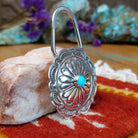 Sterling silver Arnold Blackgoat key hook with concho-style floral design and centered turquoise stone.