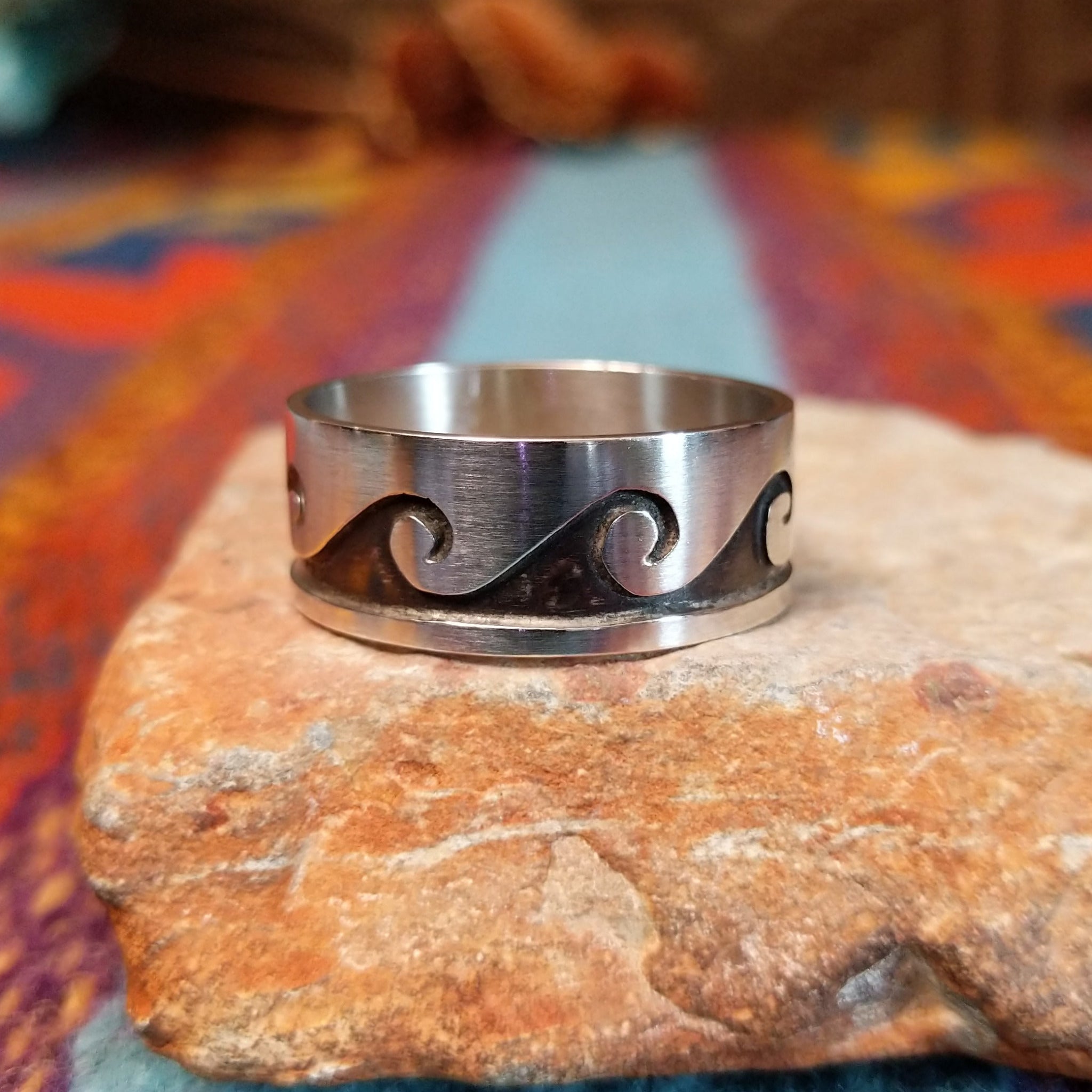 Silver Wave Ring by Lester Gene featuring a wide brushed silver band with a repeating oxidized wave pattern and polished lower border.