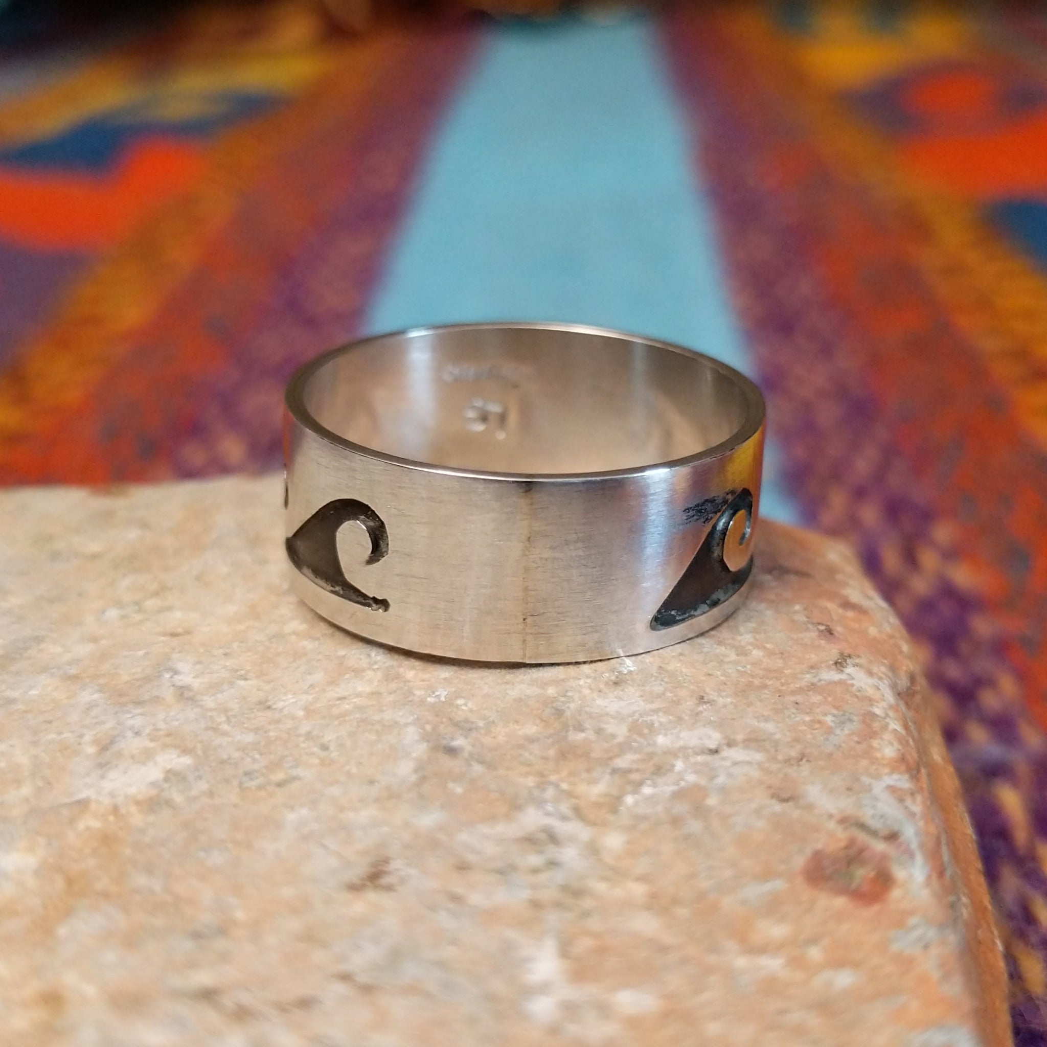 Silver Wave Ring by Lester Gene featuring a wide brushed silver band with a repeating oxidized wave pattern and polished lower border; underside view.