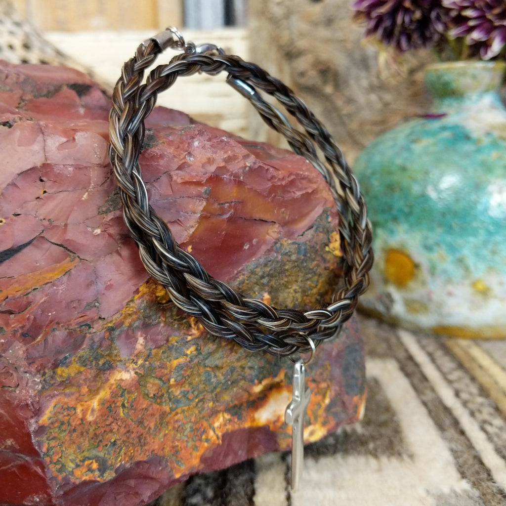 A braided horsehair necklace with a metal cross pendant.
