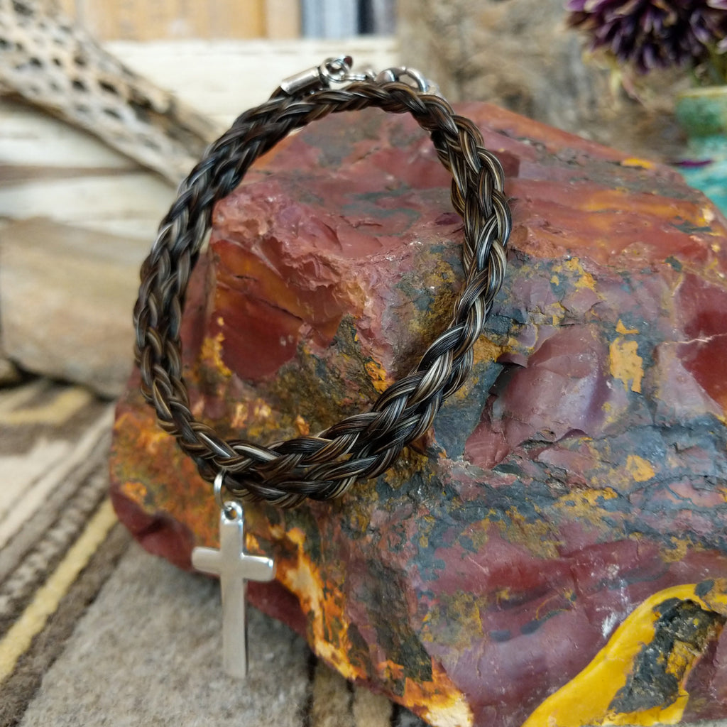 A braided horsehair necklace with a metal cross pendant.