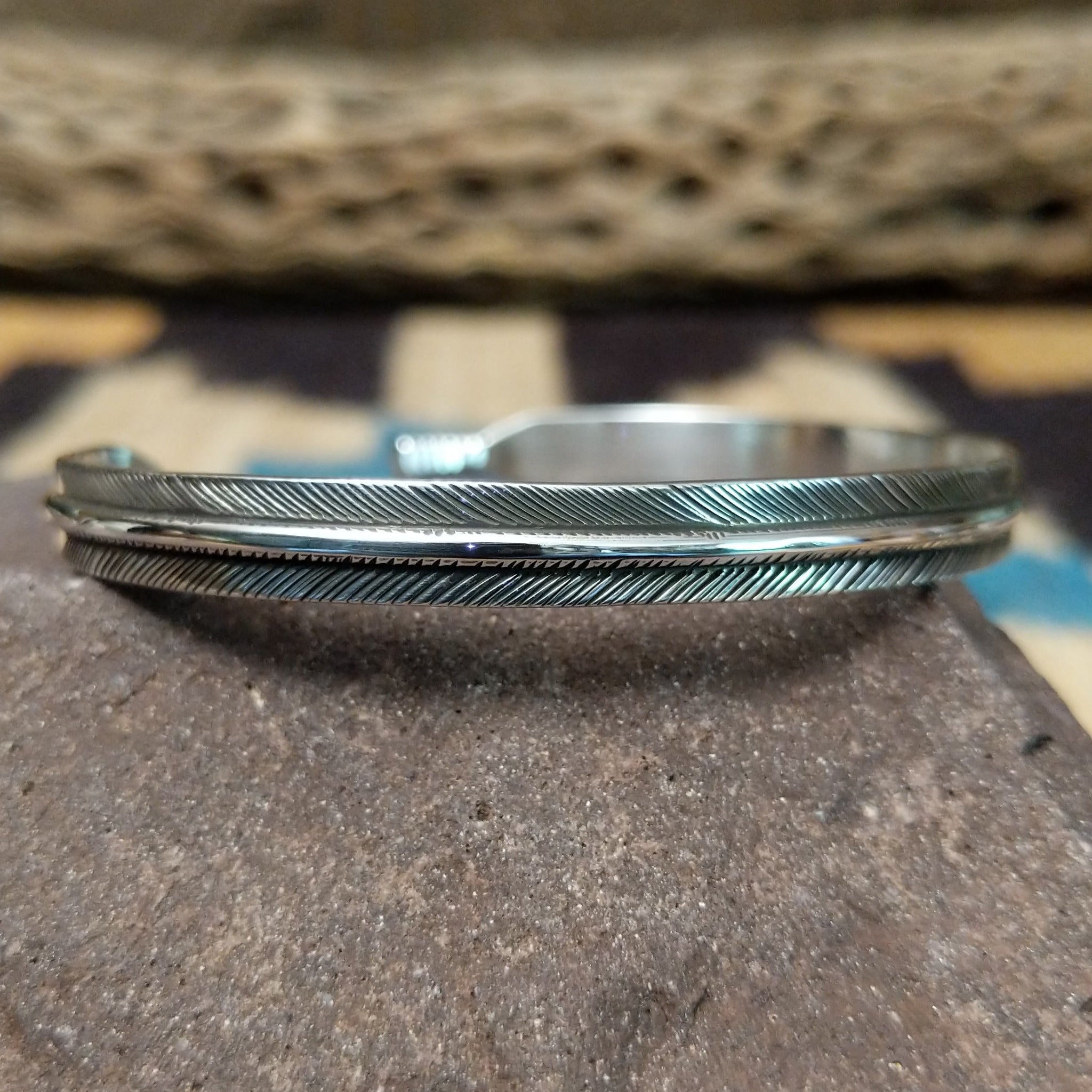 Slender silver feather cuff by Lena Platero, featuring a finely engraved sterling silver feather design in a handcrafted slim open cuff with polished finish.