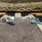 Slender silver feather cuff by Lena Platero, featuring a finely engraved sterling silver feather design in a handcrafted slim open cuff with polished finish.  Underside view.