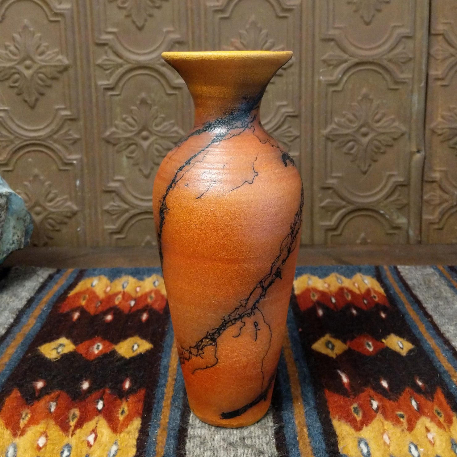 A terracotta vase with black horsehair rising along its narrow surface.