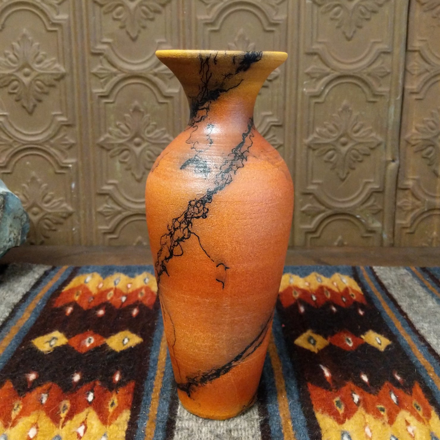 A terracotta vase with black horsehair rising along its narrow surface.