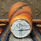 The base displays a rough terracotta texture with the artist’s signature.