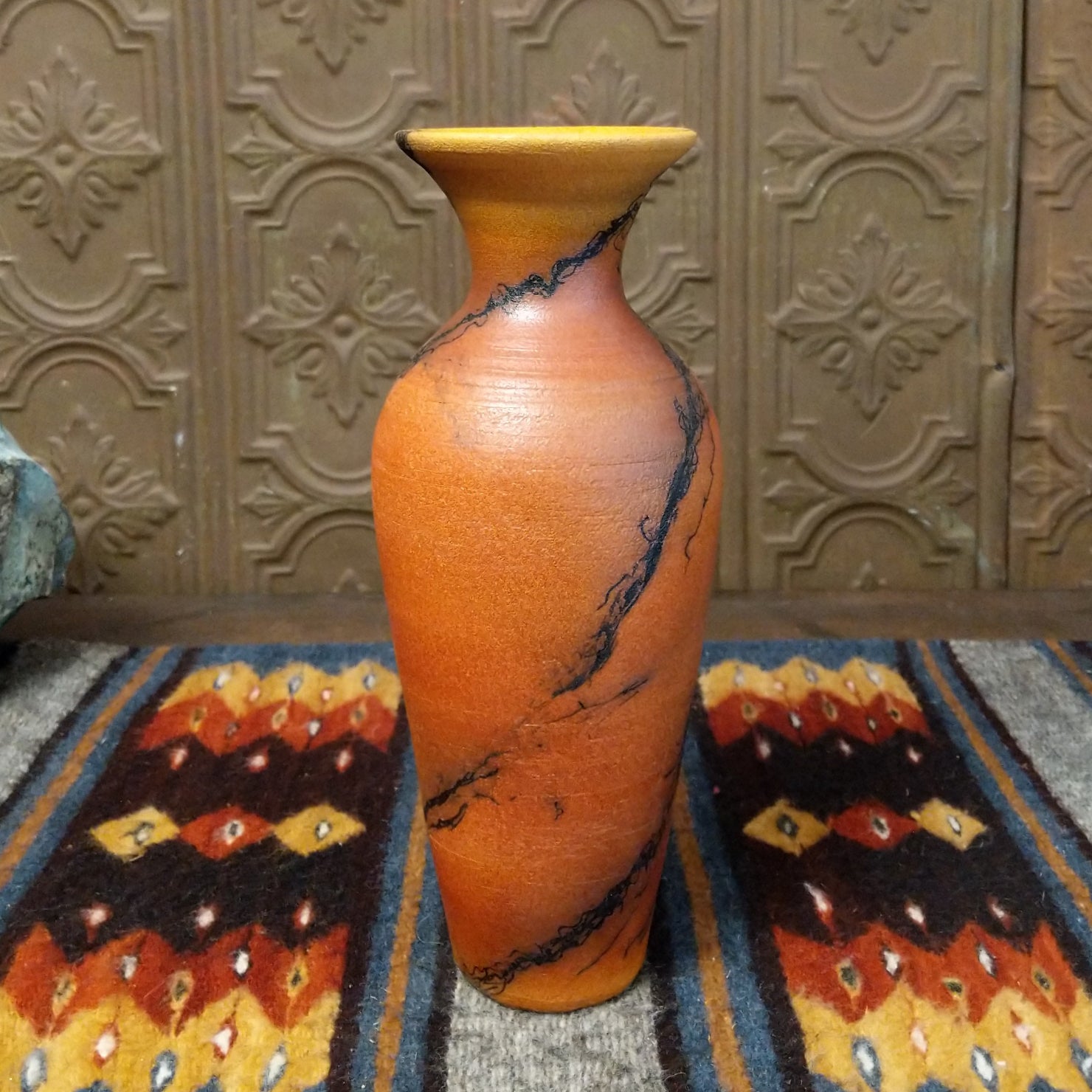 A terracotta vase with black horsehair rising along its narrow surface.