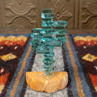 A glass cactus sculpture with translucent aqua glass mounted on a smooth sandstone base.