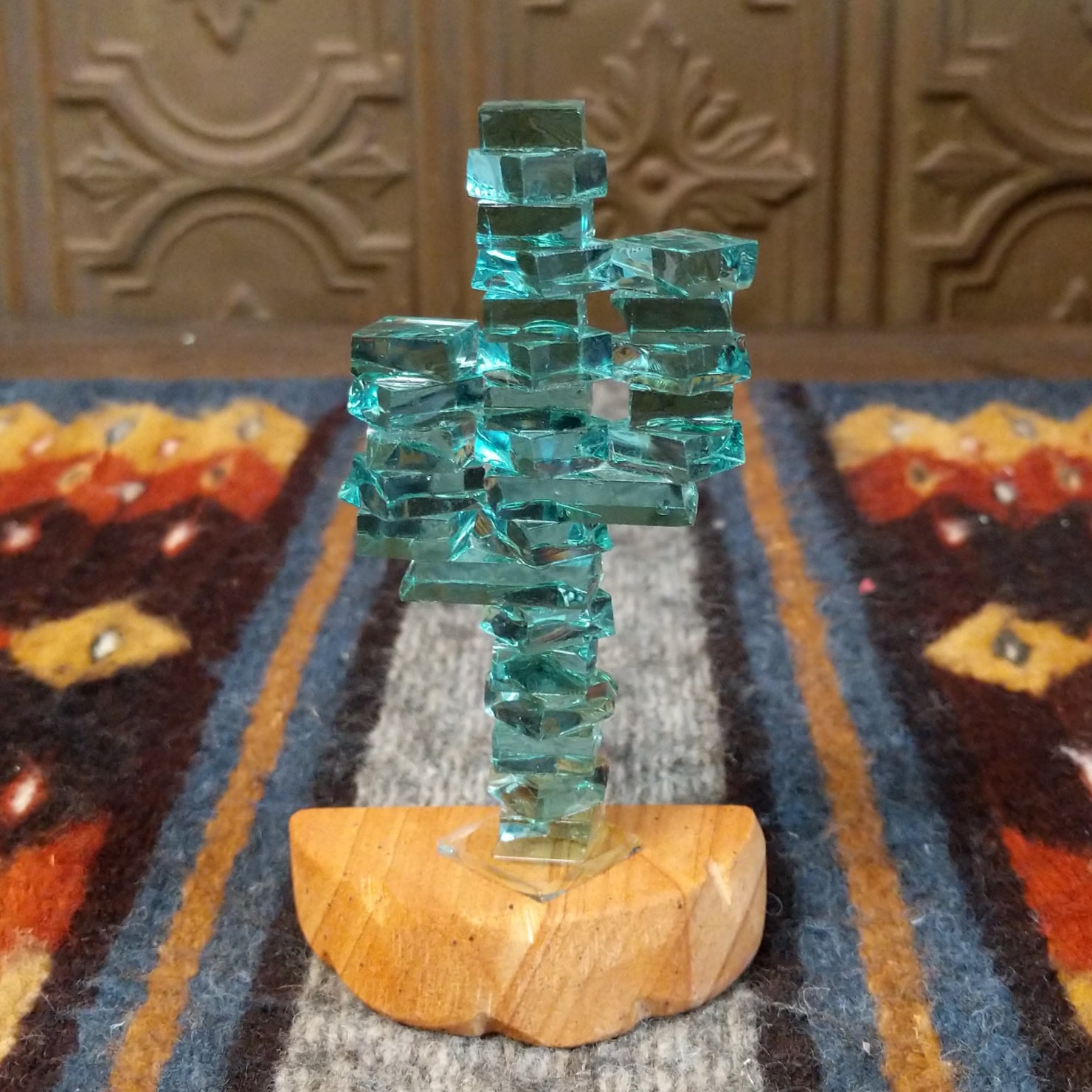 A glass cactus sculpture with translucent aqua glass mounted on a smooth sandstone base.
