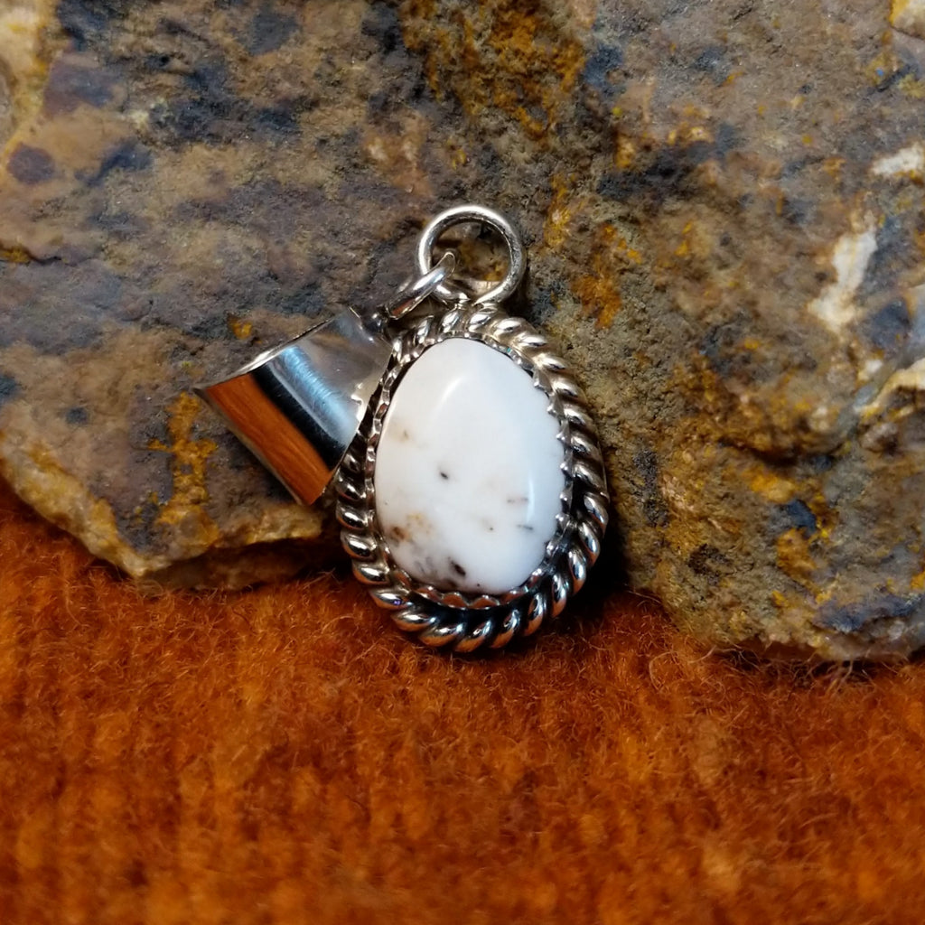 Small oval white buffalo set in notched sterling silver bezel with twisted rope accents.