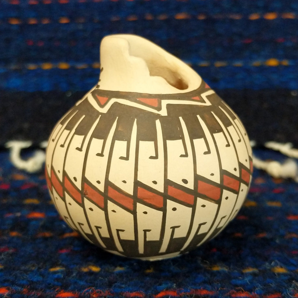 White clay body with black and red stepped patterns around the neck.
