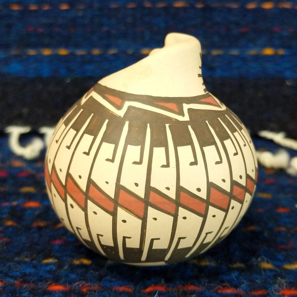 White clay body with black and red stepped patterns around the neck.