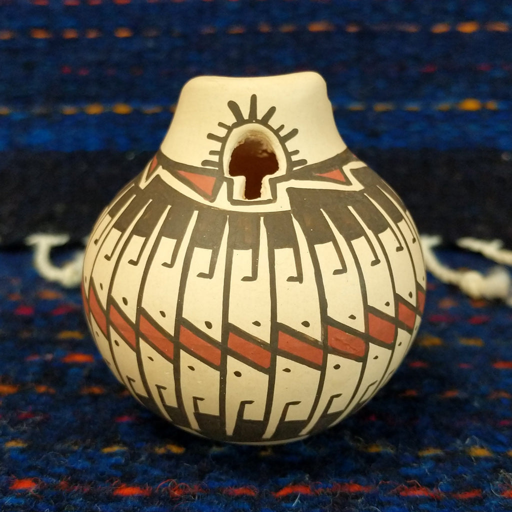 White clay body with black and red stepped patterns around the neck.