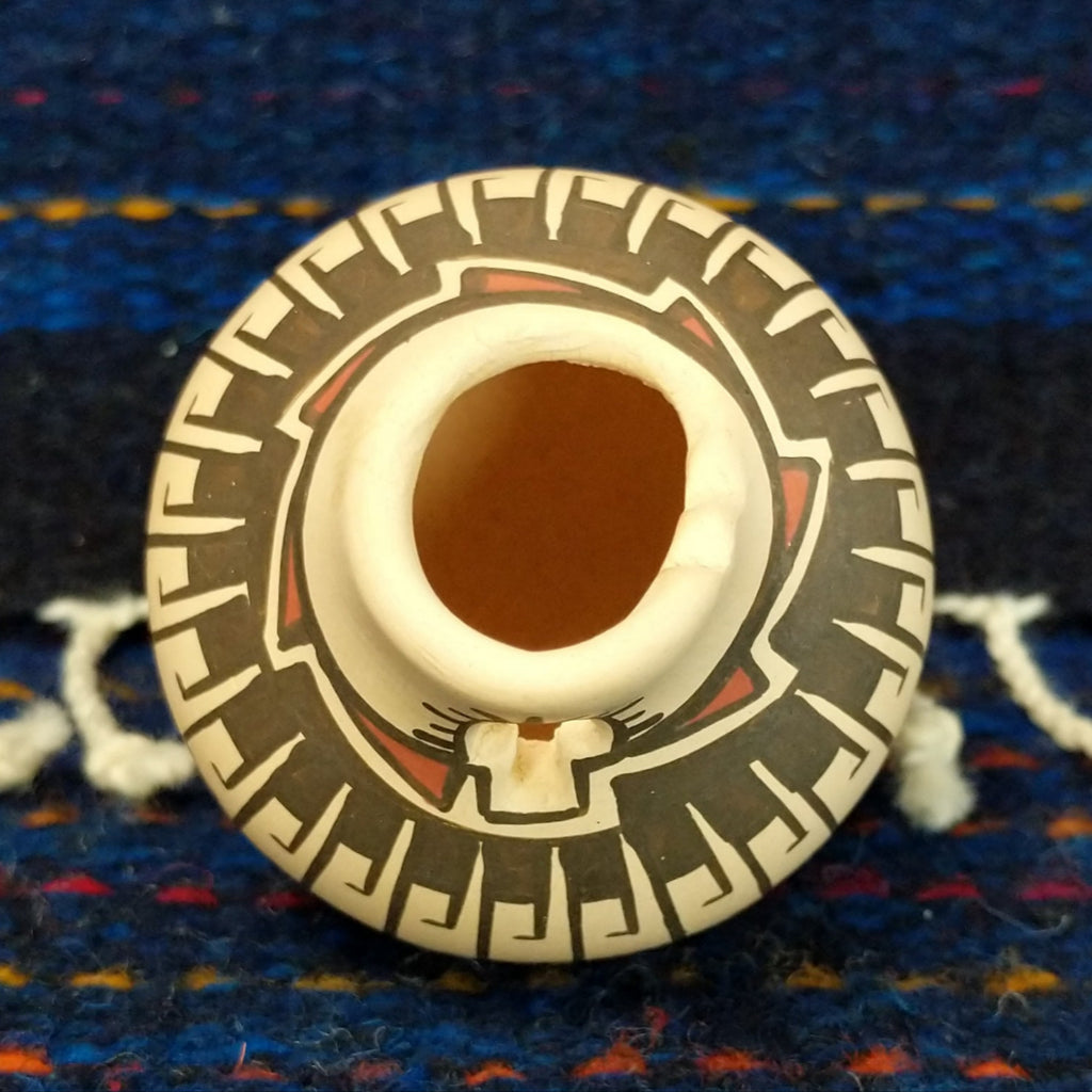 The small opening of the pot and various designs along the top.