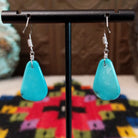 Smooth Navajo turquoise slab earrings featuring polished blue teardrop-shaped stones with minimal natural matrix, suspended from silver hooks; backside view.