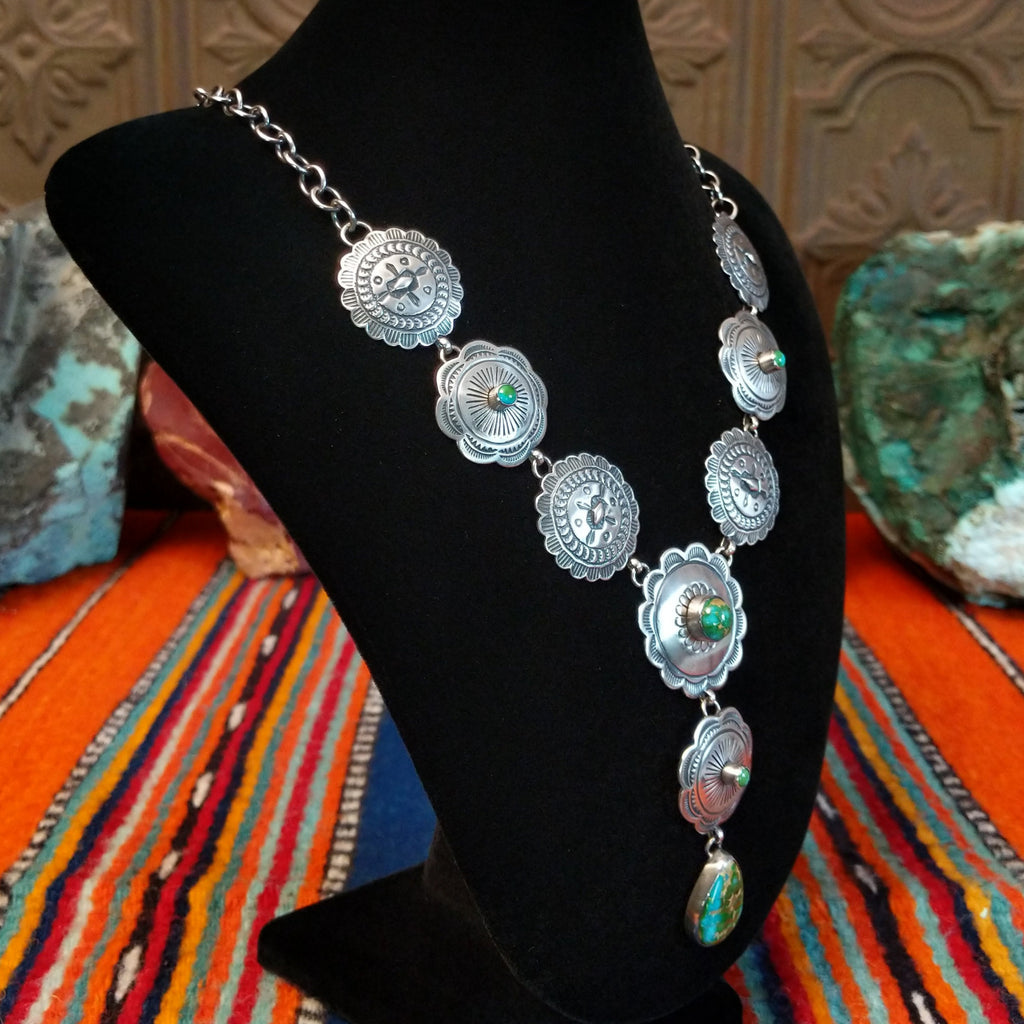 Small Sonoran Gold turquoise set in bezels that are atop the intricately decorated conchos with singural teardrop pendant.