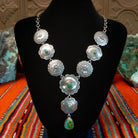 Small Sonoran Gold turquoise set in bezels that are atop the intricately decorated conchos with singural teardrop pendant.