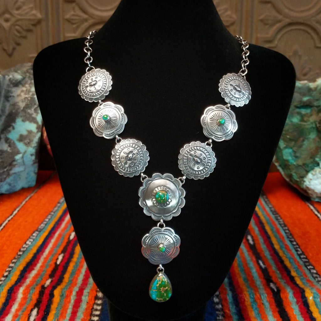 Small Sonoran Gold turquoise set in bezels that are atop the intricately decorated conchos with singural teardrop pendant.