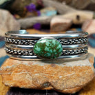 Handcrafted sterling silver cuff by H.R.M. featuring an oval Sonoran Gold turquoise cabochon centered between polished silver bands with dual oxidized chain accents.