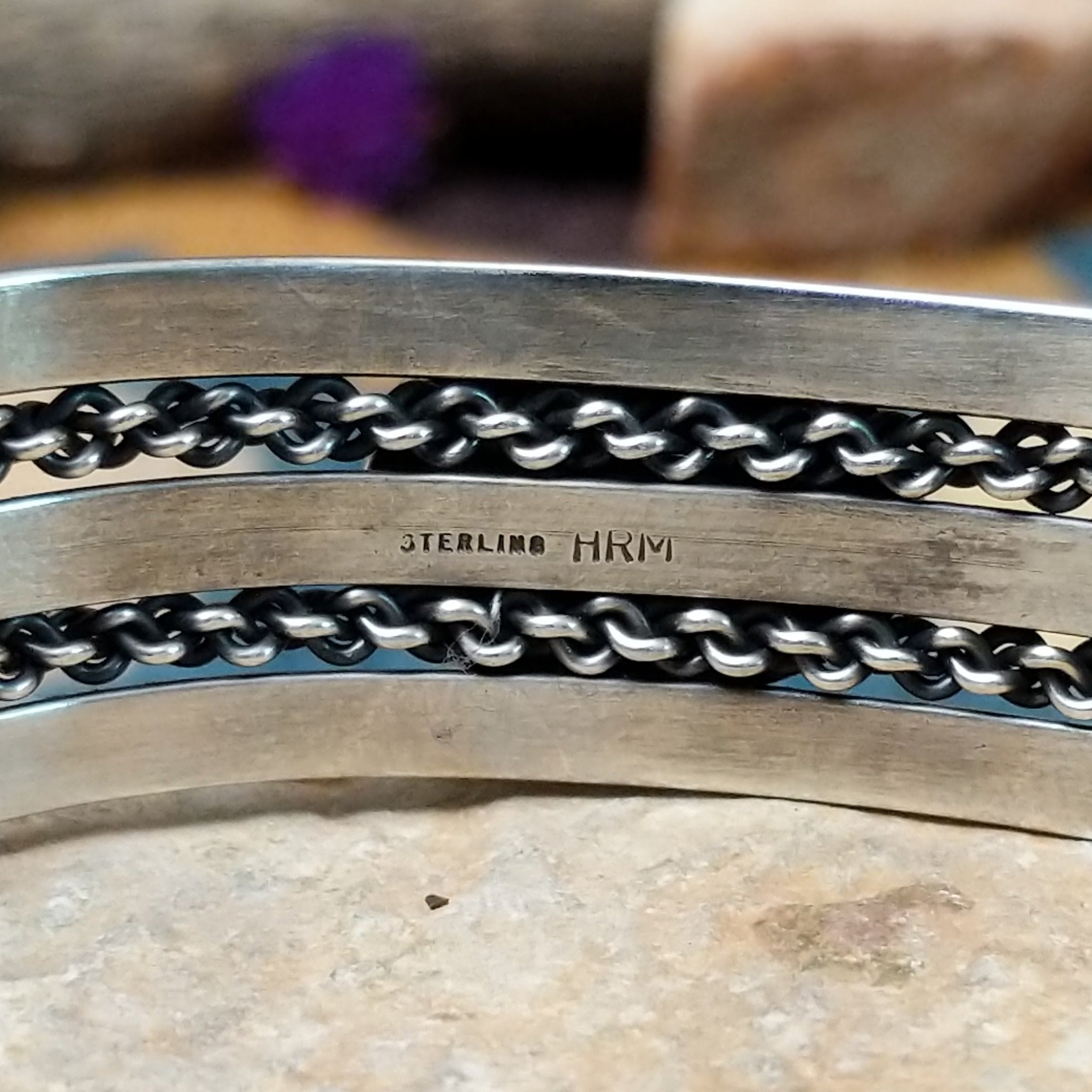 Handcrafted sterling silver cuff by H.R.M. featuring an oval Sonoran Gold turquoise cabochon centered between polished silver bands with dual oxidized chain accents; artisan and Sterling Silver stamp.
